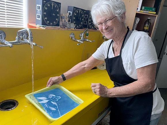 Collective Member Barbara rinsing a cyanotype for World Cyanotype Day